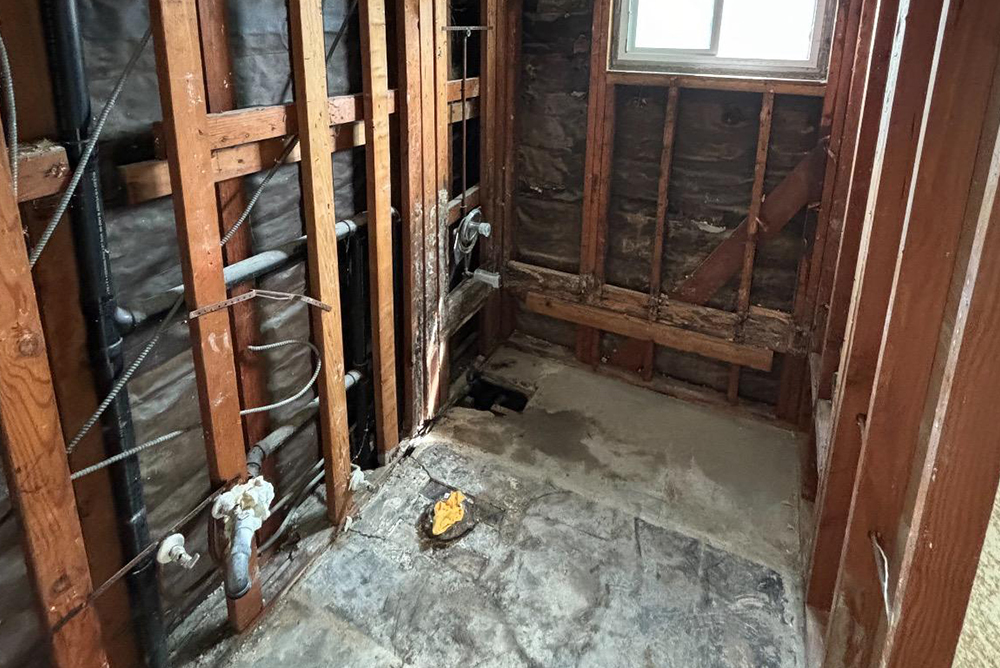 exposed wall framing and flooring showing water damage demolition work